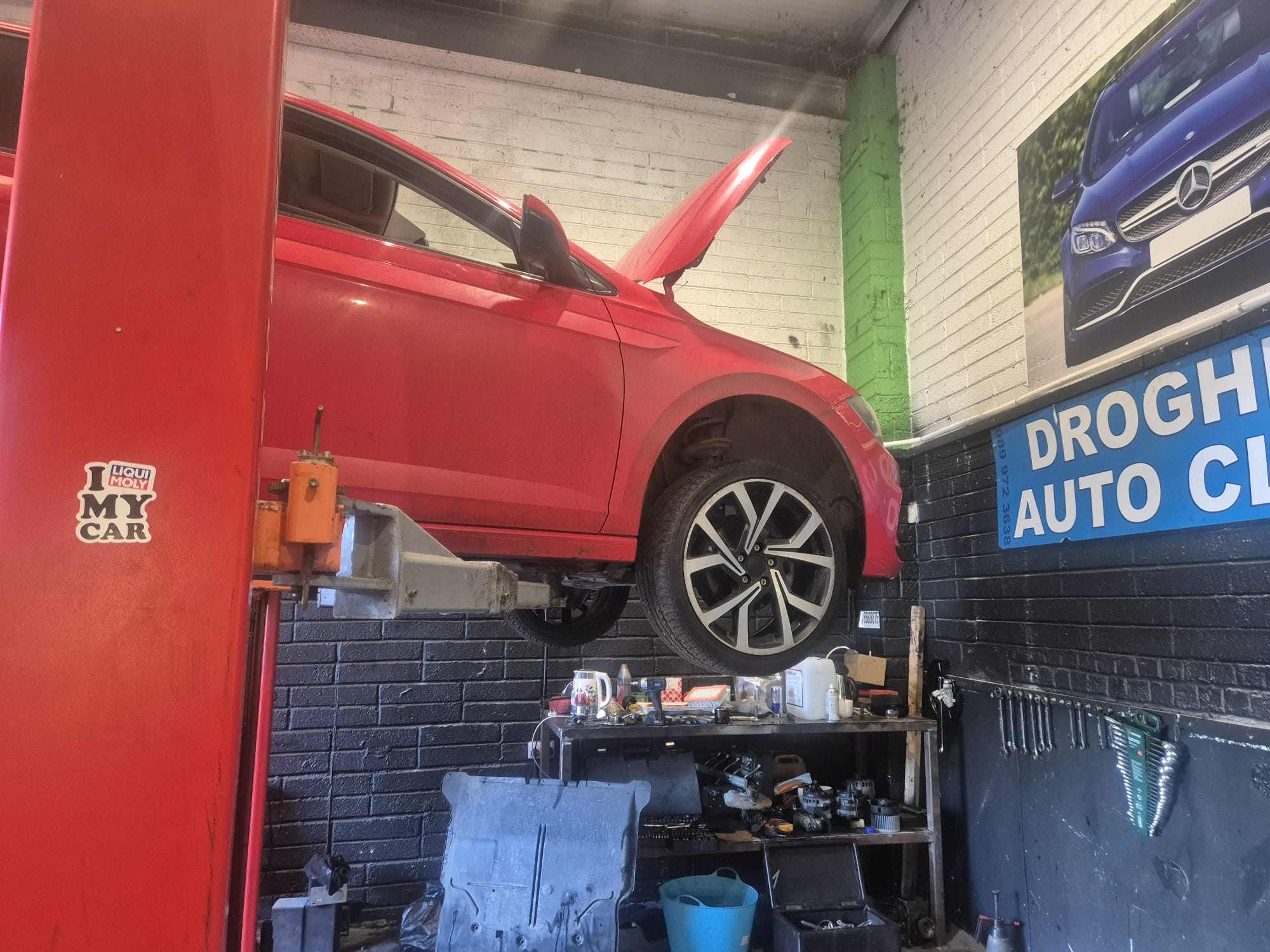 Red hatchback on lift for service